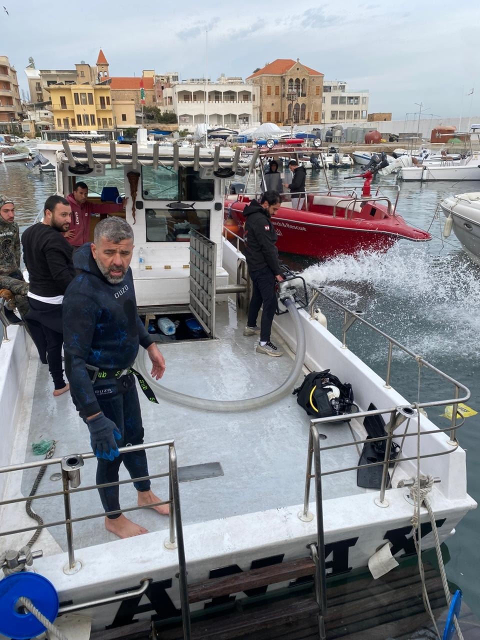 بالصور: سحب مركب سياحي بعد غرقه بالكامل في ميناء صور صباحا