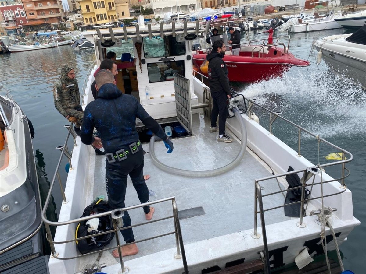 بالصور: سحب مركب سياحي بعد غرقه بالكامل في ميناء صور صباحا