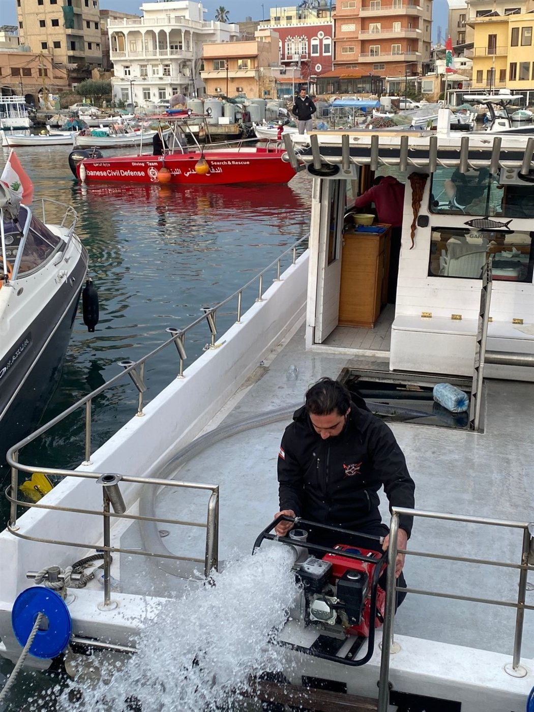 بالصور: سحب مركب سياحي بعد غرقه بالكامل في ميناء صور صباحا